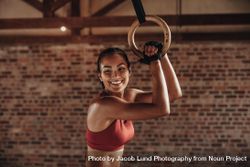 Fit woman holding gymnast rings at the gym and smiling bDpGJb