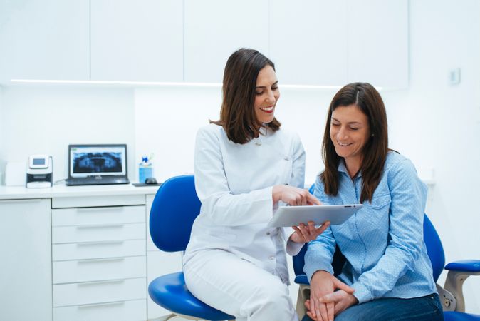 Dentist speaking with client showing document with information