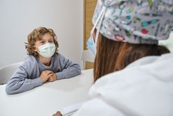 Child in mask visiting dentist for dental checkup