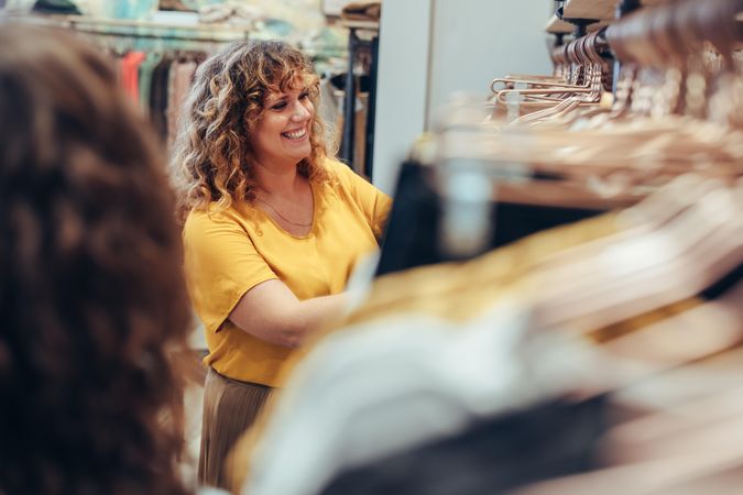 Smiling shopper in retail clothing store looking at clothes