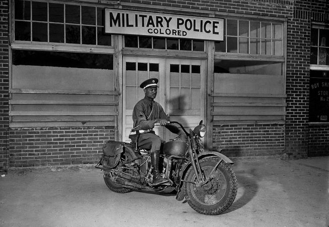 Black American soldier sitting on motorbike during World War II