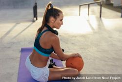 Female in sportswear sitting on exercise mat with a ball 568Mdb