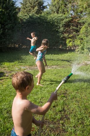 Little kids in swimwear having fun with splashing water