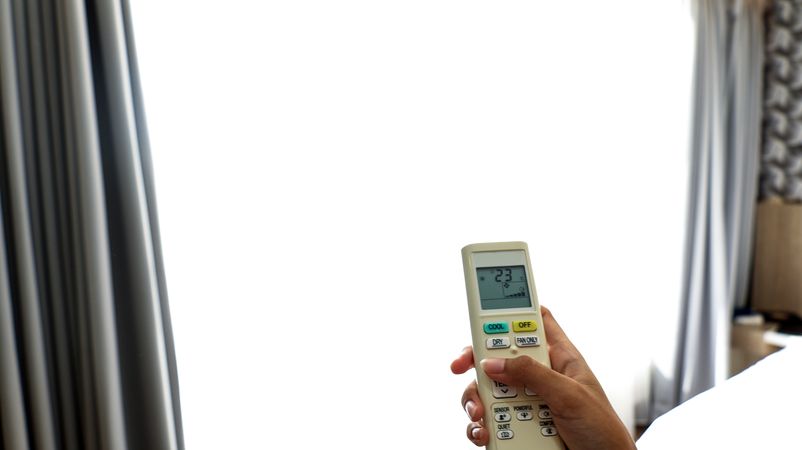 Woman Operating Remote Controller on Air Conditioner Inside the Room
