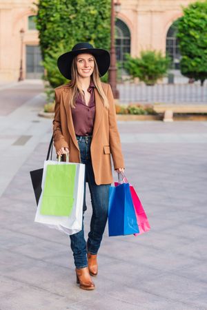 Content female in trendy wear doing shopping at city street