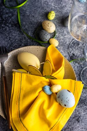 Easter table setting with pastel eggs and yellow napkin
