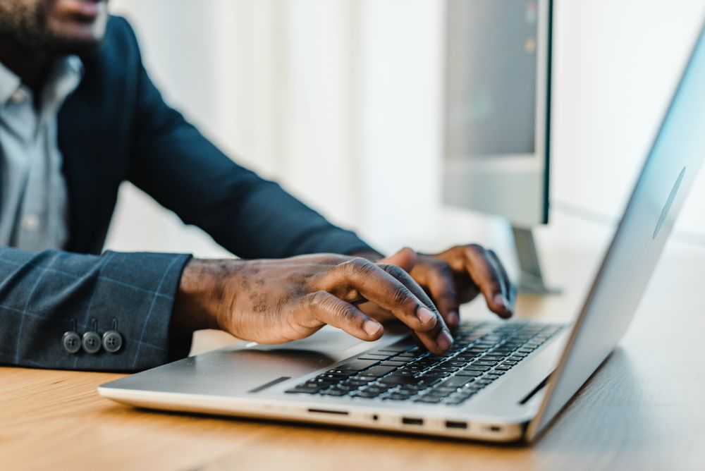 Crop Black businessman typing on laptop