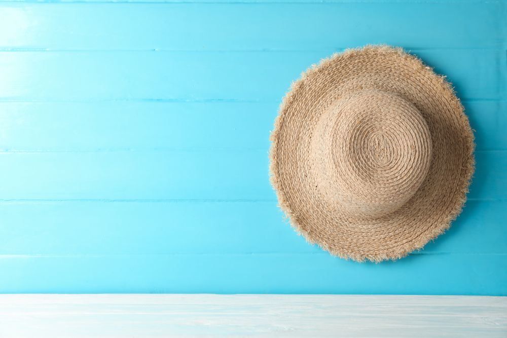 Straw hat on table against color background, space for text. Summer vacation backdrop