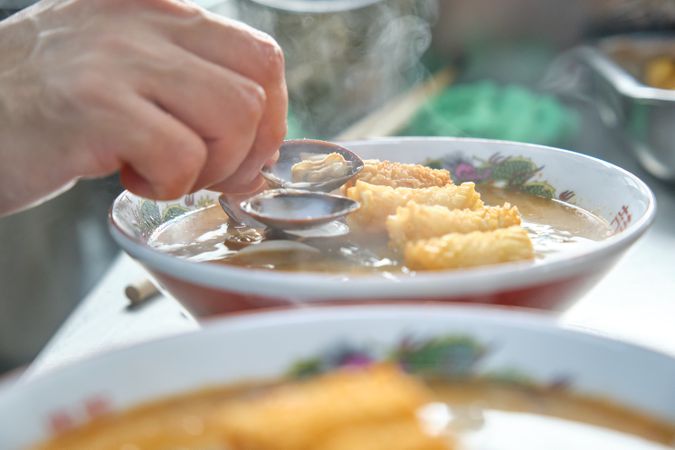 Cook preparing traditional oriental soup with mussels
