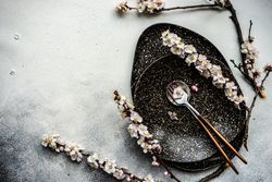 Minimalistic table setting with apricot blossom on elegant dark table setting