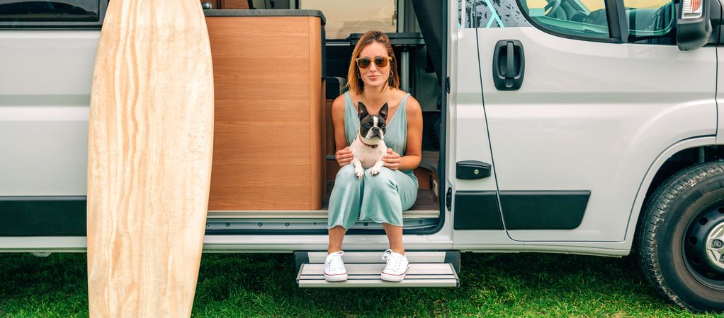 Woman sitting on stoop of motorhome door with cute dog on her lap