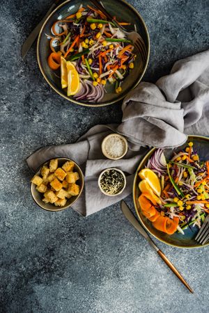 Top view of two fresh salad with finely chopped vegetables and lemon slices in bowl on table with copy space