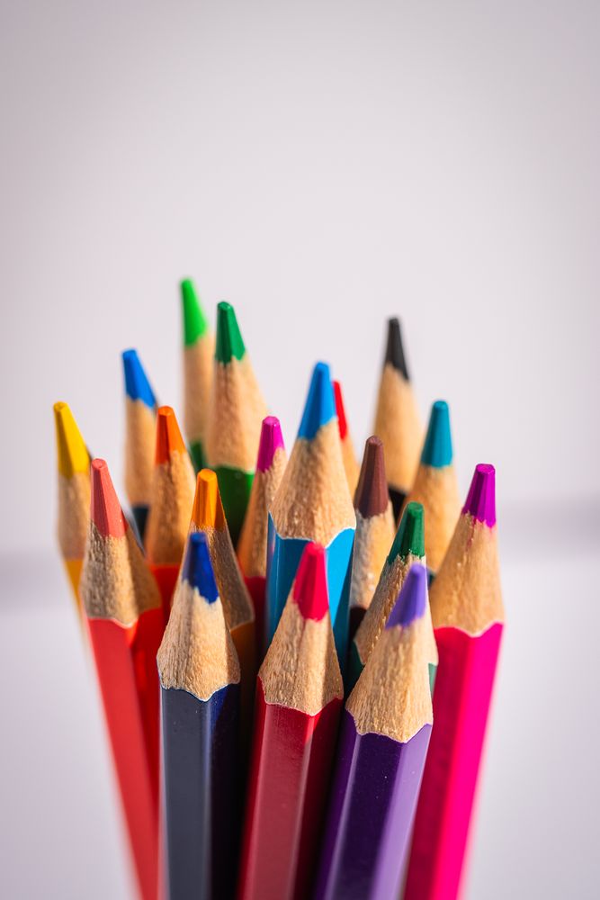 A bunch of colored pencils are lined up in a row