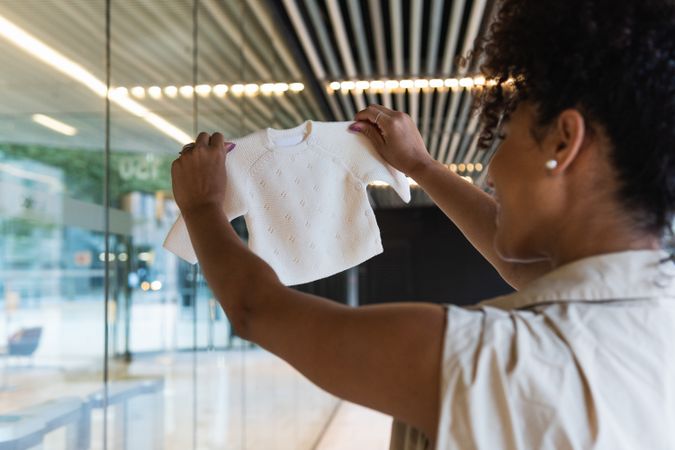 Pregnant Black woman with baby clothes near glass building