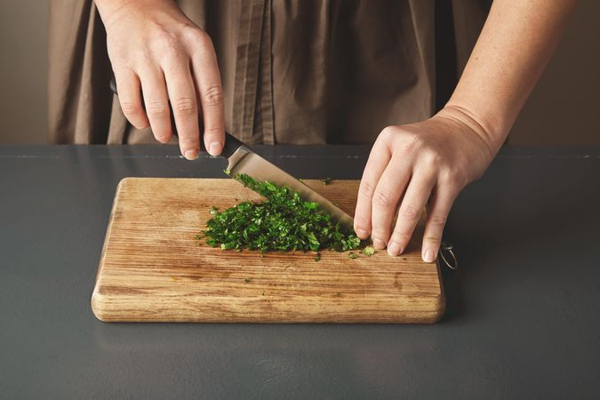 Woman chopping parsley on breadboard