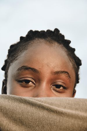 Young woman covering her lower face with brown textile