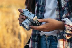 Unrecognizable woman taking photos with analog camera at sunset