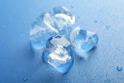 Top view of four melting ice cubed on blue table