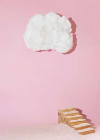 Wooden staircase leading to cotton cloud on pink background