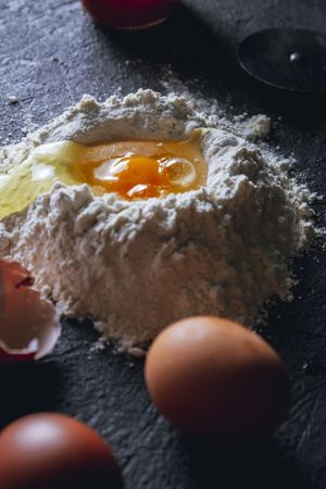 Broken egg and flour on dark background