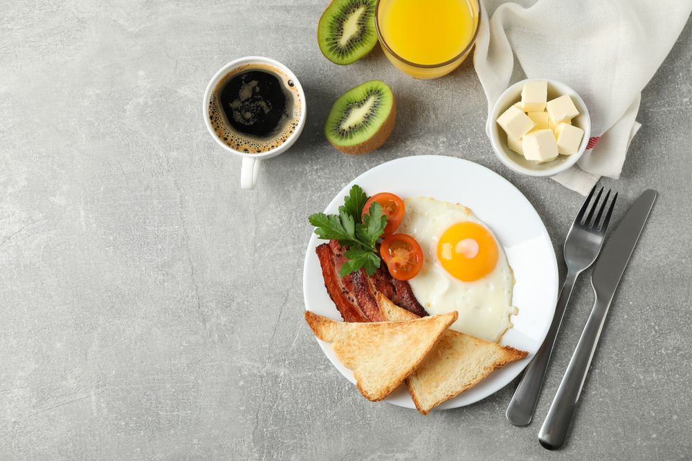 Top view of breakfast for one with eggs, toast, bacon and coffee, copy space