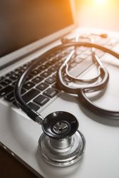 Medical Stethoscope Resting on Laptop Computer Keyboard.