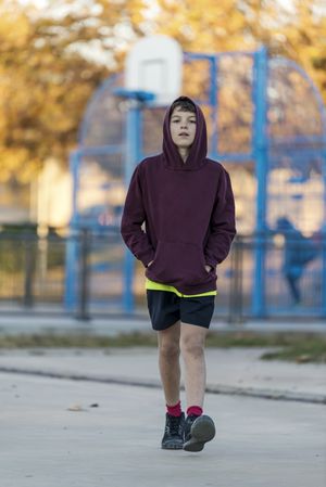 Front view of a young hooded boy walking towards camera