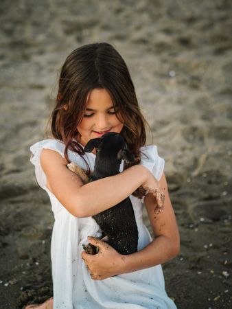 Girl with little dog on sandy beach