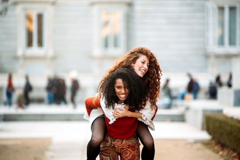 Two cheerful young women playing piggy back