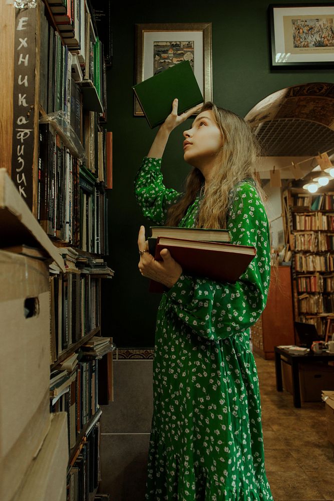 Girl putting a book back to bookshelf
