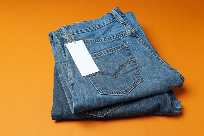 Blue jeans folded on orange background