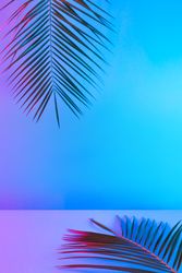 Tropical and palm leaves in vibrant bold gradient holographic neon colors, with copy space