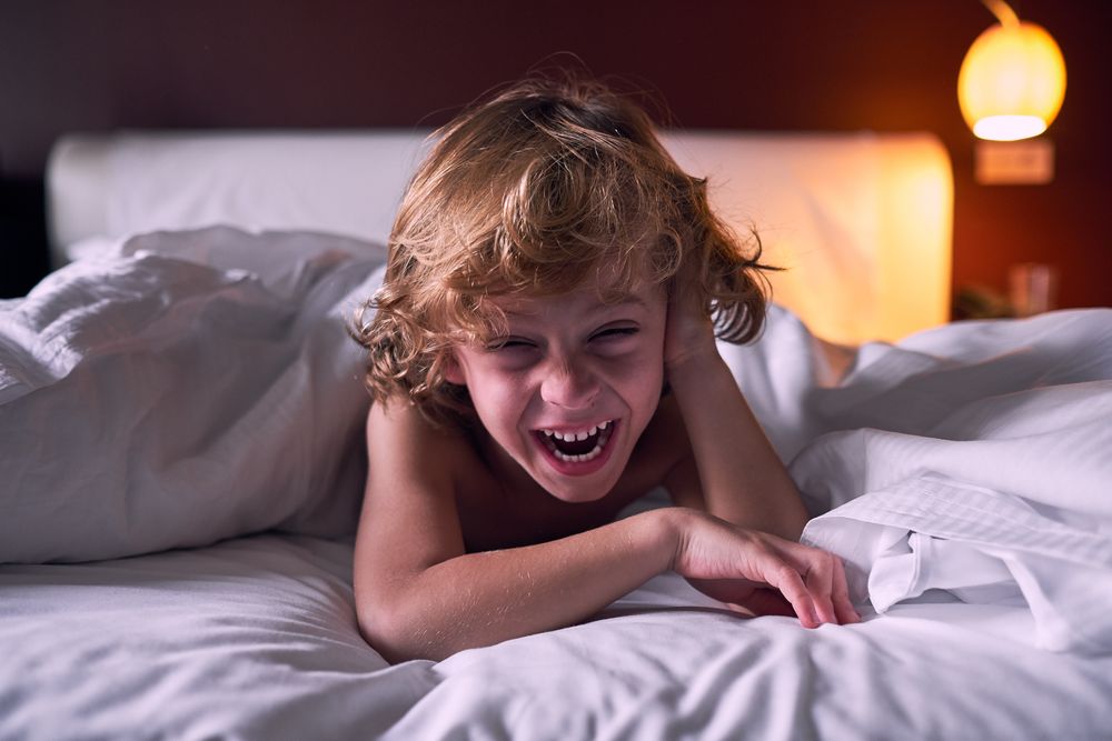 Excited child laughing on bed