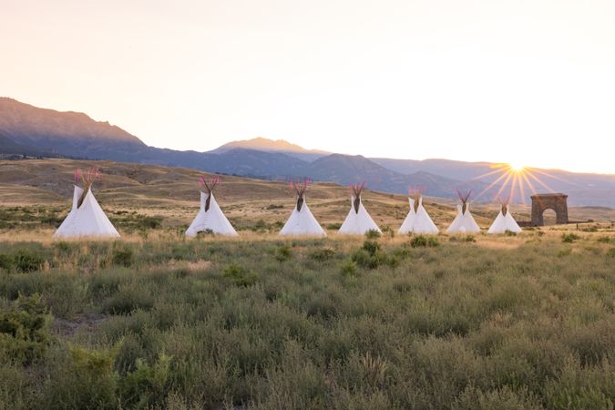 Montana, United States - August 17, 2022: Line of teepees in the mountains at dusk with arch and sun flare