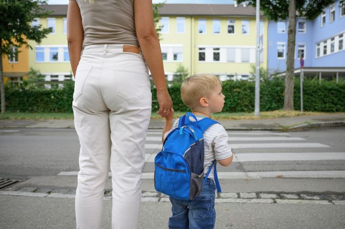 A mother taking her little son to the kindergarten and crossing a street