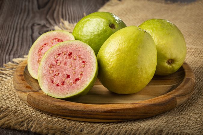 Fresh sliced guavas on wooden table.