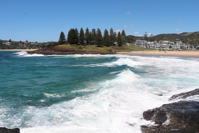 Waves crash on the shore at a picturesque coastal location under a clear blue sky