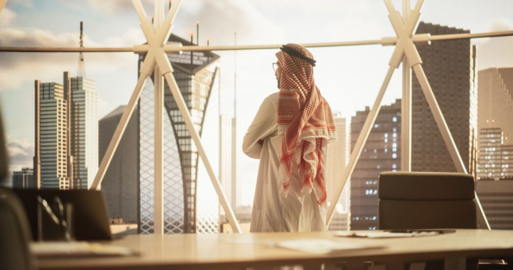 Successful Muslim Businessman Standing in His Modern Office Looking out of the Window on Big City with Skyscrapers.