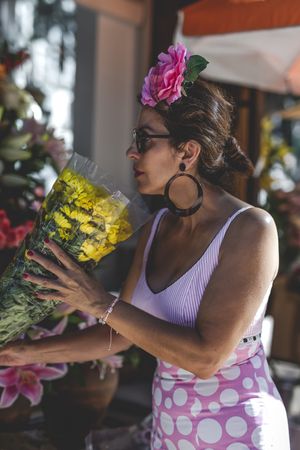 Modern woman in flamenco dress enjoying flowers at florist shop