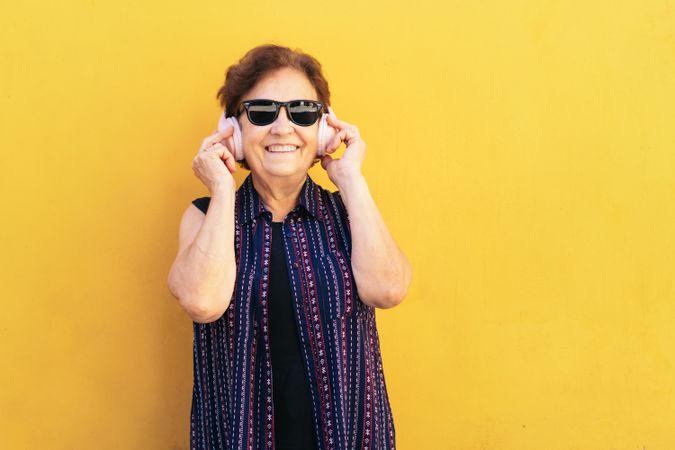 Stylish older woman in sunglasses listening to music with headphones