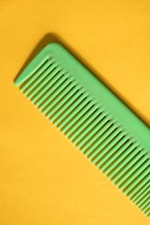Bright green hair comb on yellow background
