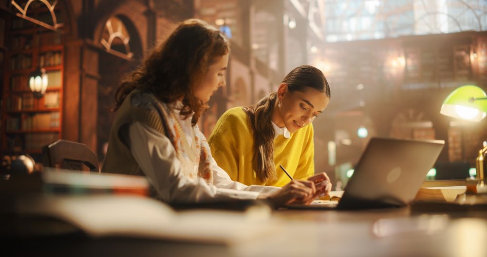 Engaged Young Women Collaborating on Academic Research in a Vintage Library Setting