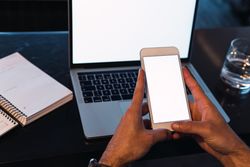 Anonymous man browsing smartphone near laptop