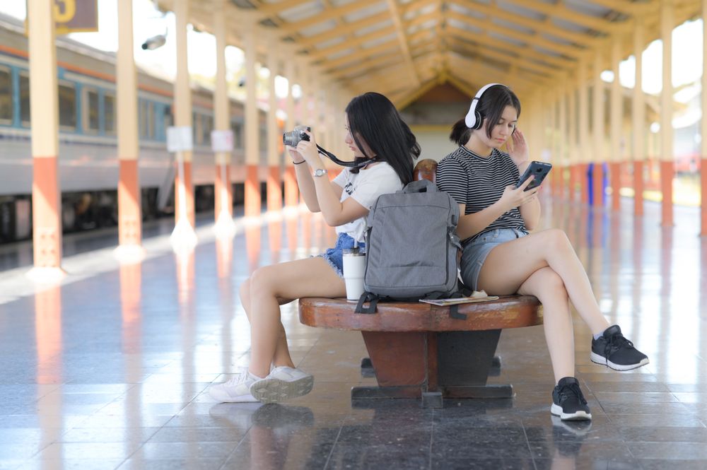 Two female tourists waiting for a train on a platform for a trip