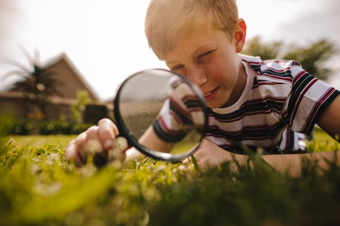 Boy looking through magnifying glass on a sunny day