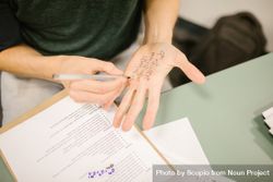 Person writing a math equation on their hand as part of cheating on exam 47qGz0