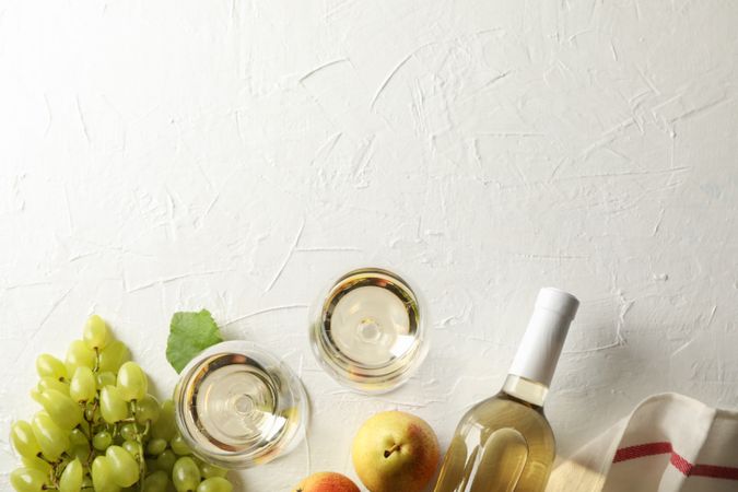 Pears, grape, bottle and glass with wine on plain background, top view