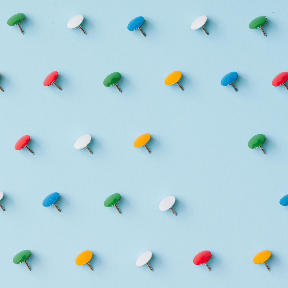 Colorful thumbtacks on blue background