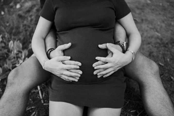 Expecting couple holding hands on belly
