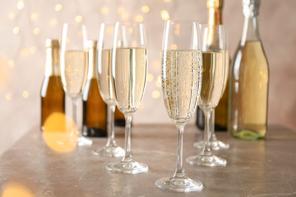 Champagne glasses and bottles on decorated background, space for text